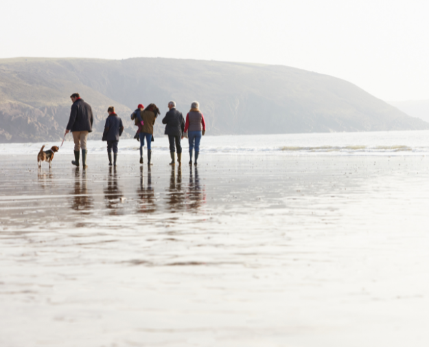 A family walking their dog along a beach in Cornwall in December